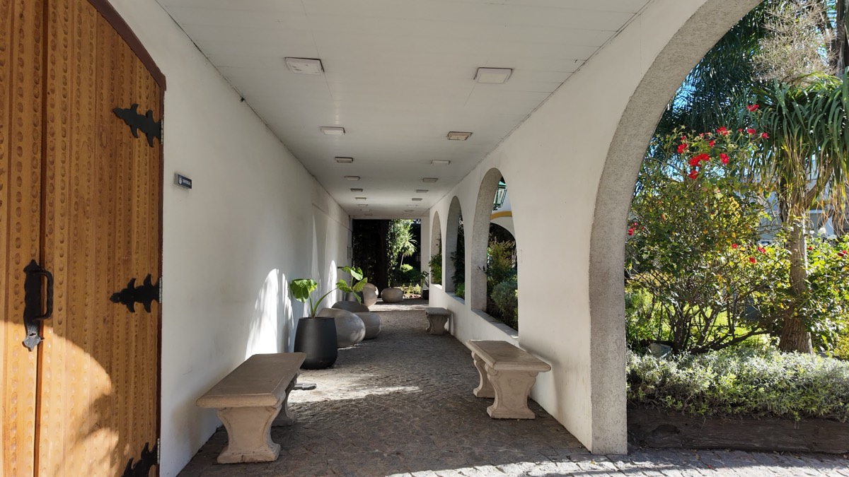 Galería exterior con arcos coloniales y bancos de piedra